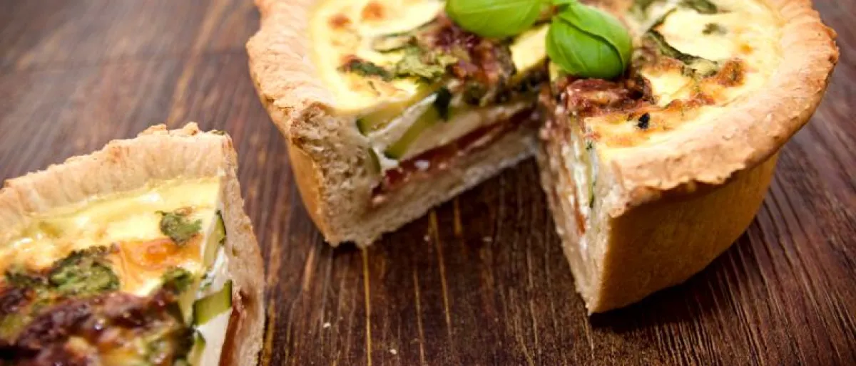 A delicious deep layered Mediterranean quiche with basil garnish